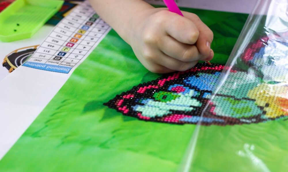 child working on diamond painting kit -butterfly